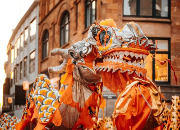Chinees Nieuwjaar in de straten van Kopenhagen, Denemarken met veel mensen in oranje witte kostuums en een grote draak die boven de menigte uitstijgt